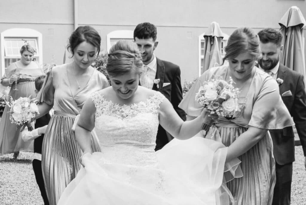 Bride and Groom walking with bridesmaids and groomsmen in the Woodford Dolmen Hotel Gardens
